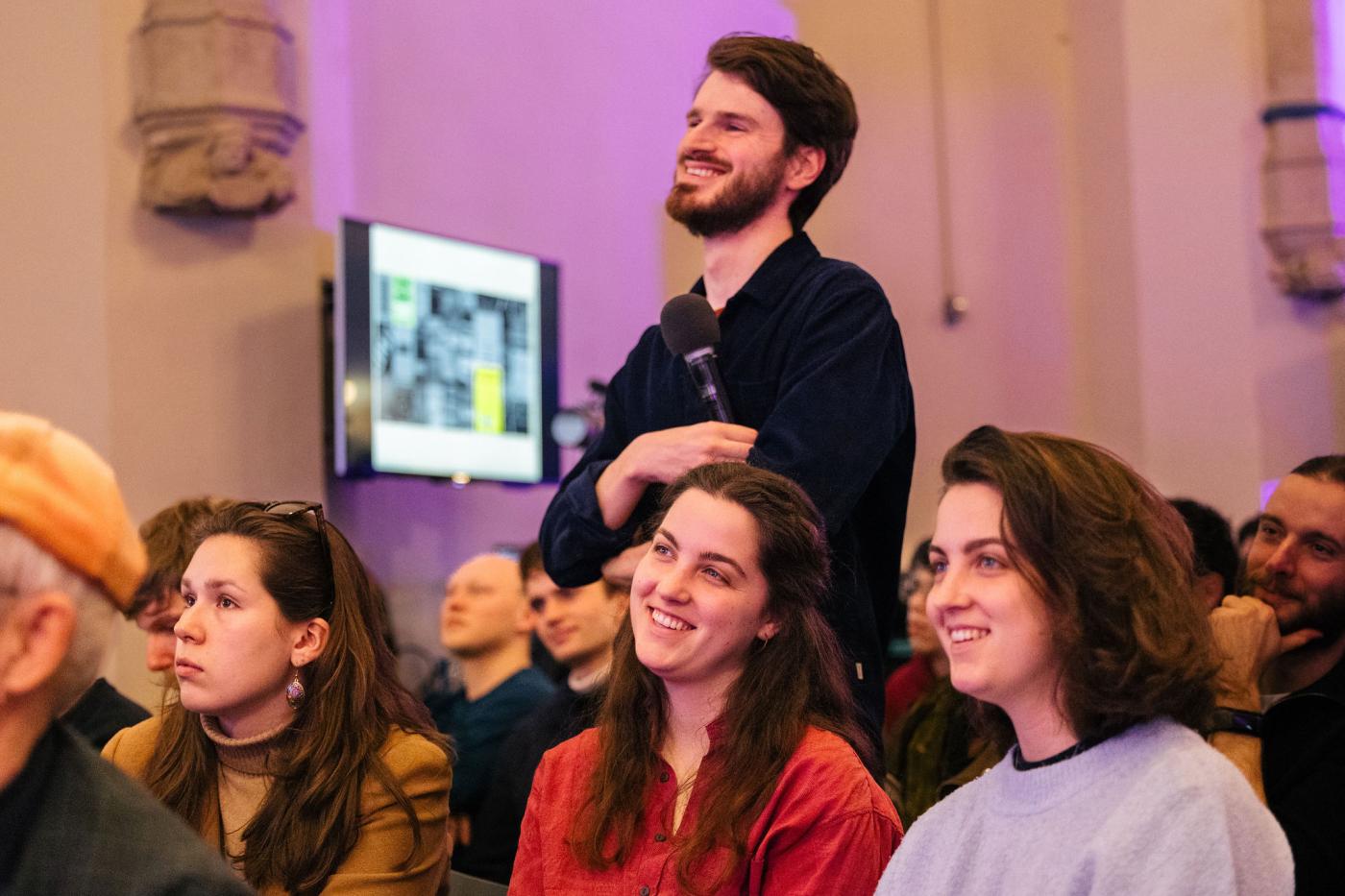 Programmamaker Erwin Maas staat tussen studenten tijdens een Studium Generale lezing
