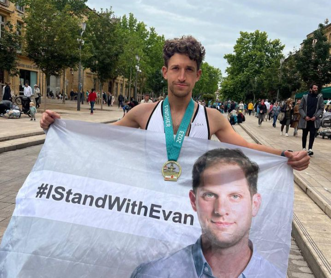 Pjotr Sauer carrying a flag with a picture of journalist Evan Gershcovich