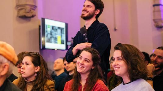 Programmamaker Erwin Maas staat tussen studenten tijdens een Studium Generale lezing